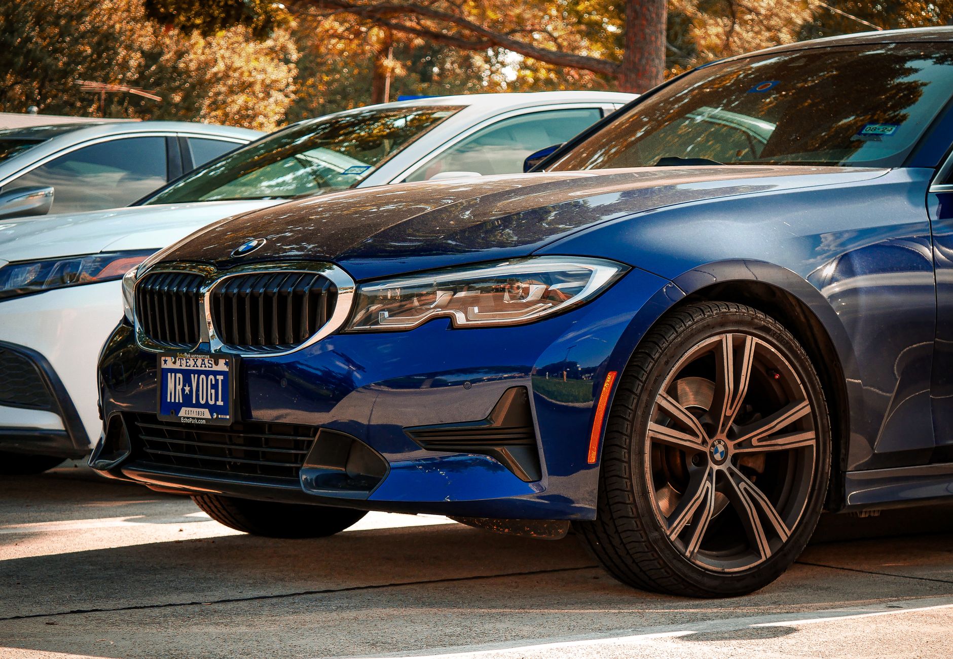 Blue BMW 330i parked outdoors in Arlington, Texas, under sunny skies.