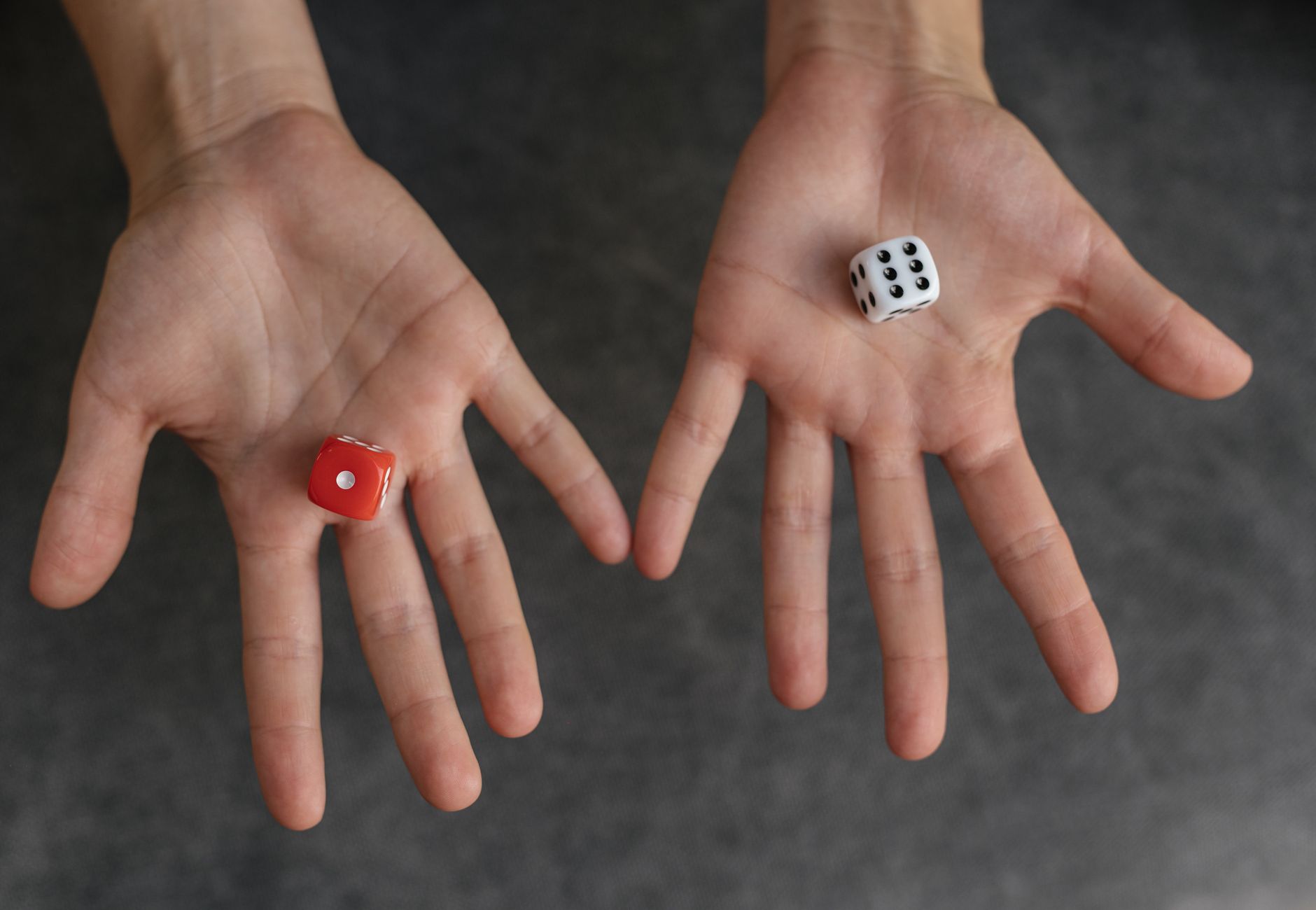 Close-up image of hands holding red and white dice against a blurred background.