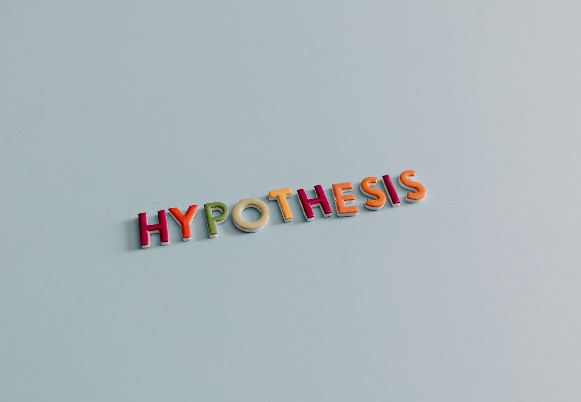 Multicolored letters spell 'HYPOTHESIS' on a light blue surface, conveying research and creativity.