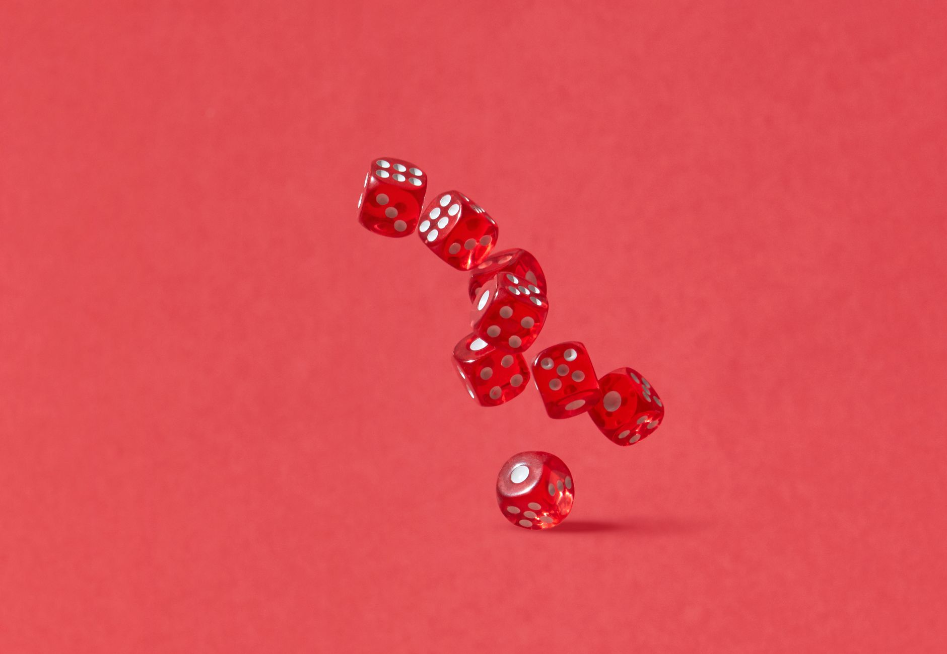 Dynamic shot of red dice tumbling mid-air against a crimson backdrop, perfect for gaming themes.