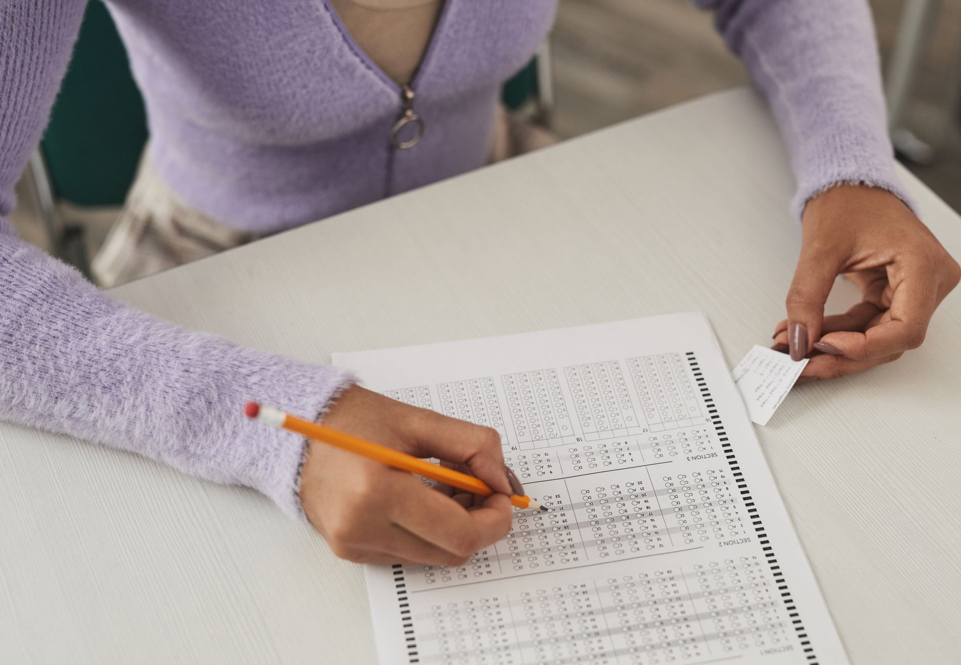 Close-up of a person using a cheat sheet while answering a multiple-choice exam.