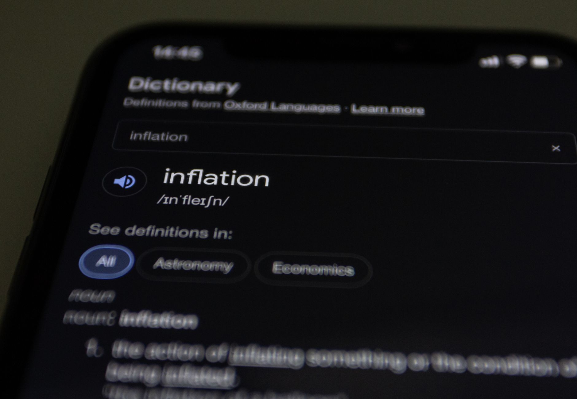 Close-up of a smartphone screen showing the word inflation defined in a dictionary app.